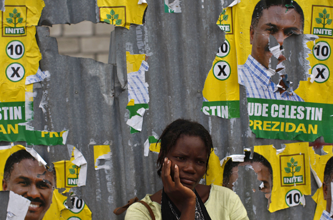 A resident looks on next to Haiti presidential election posters
