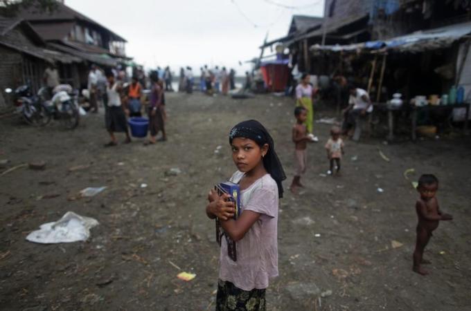 Myanmar Rohingya girl carries her books through a fish market on her way to school in the town of Sittwe