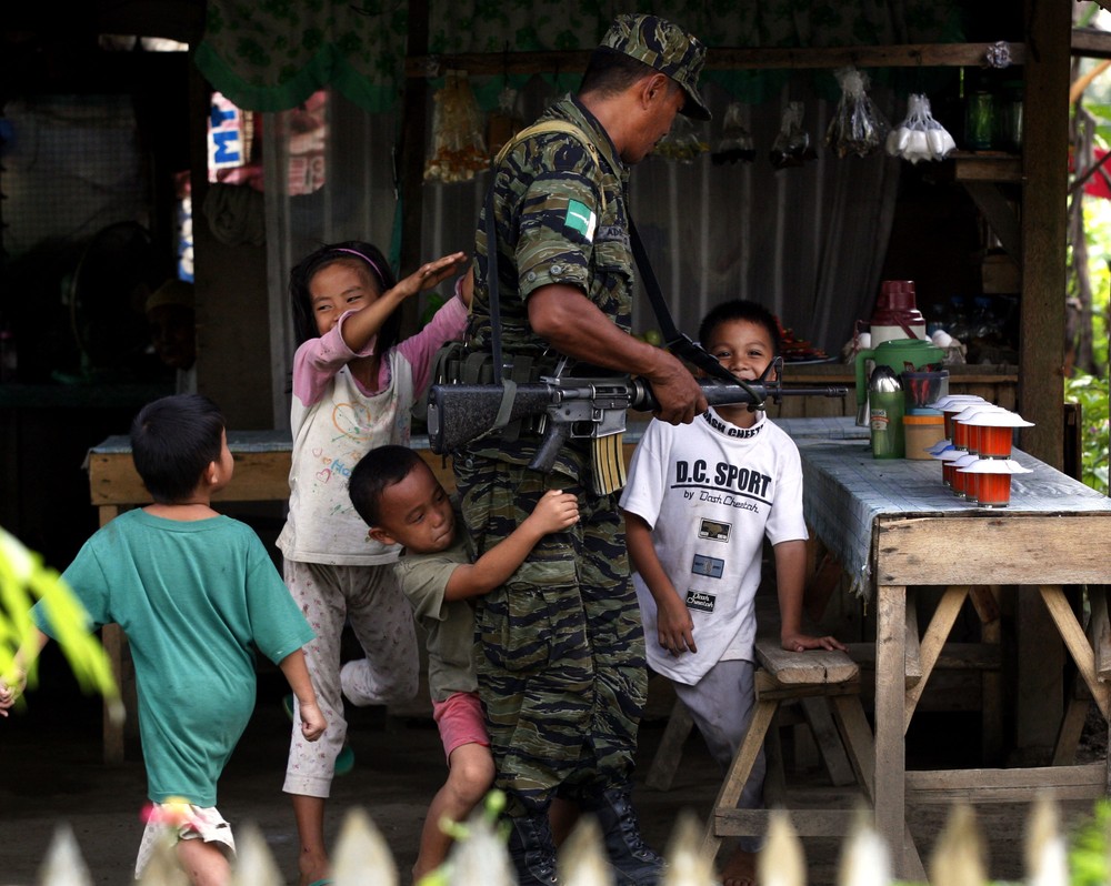 A group of children play with a Muslim rebel during a lull in fighting inside the rebel(***)s Camp Darapanan on Mindanao island in the southern Philippines. 