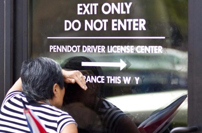 A woman peers in through a glass door at a Pennsylvania Department of Transportation office in Philadelphia to get a voter ID card