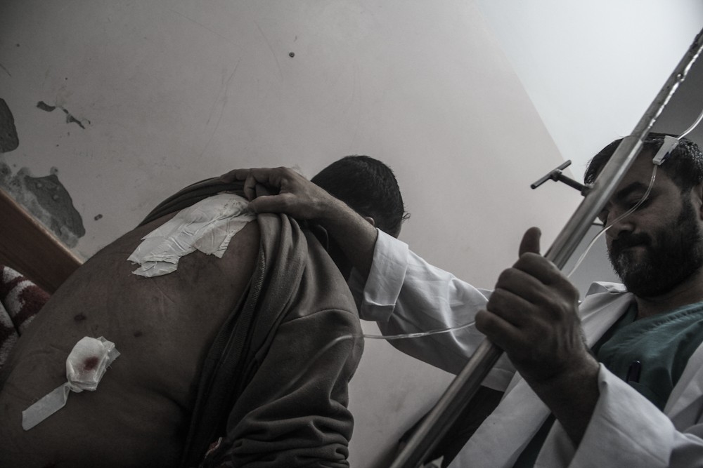 A doctor in Kuwait Hospital in Rafah holds an IV for a patient hit with shrapnel in the back after an explosion on his street. Medics in Gaza are trying to help the dozens of injured constantly flowing into hospitals.