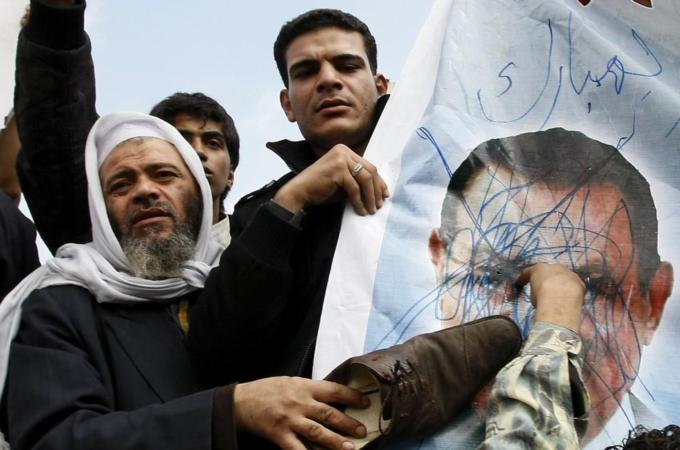 Egyptian demonstrators use a shoe to hit