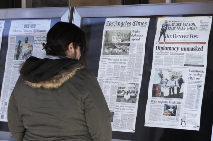 A woman reads Monday''s U.S. newspapers front pages outside the Newseum in Washington