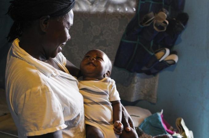 A Haitian child who will be placed for adoption is held by a caretaker at an orphanage outside of Port-au-Prince