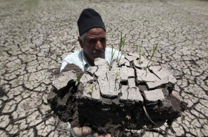 An Egyptian farmer holds a handful of soil to show the dryness of the land due to drought in a farm formerly irrigated by the river Nile, in Al-Dakahlya