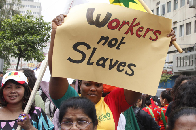 A migrant domestic worker holds up a placard during a parade in Beirut, to support the rights of migrant domestic workers in Lebanon, ahead of May Day