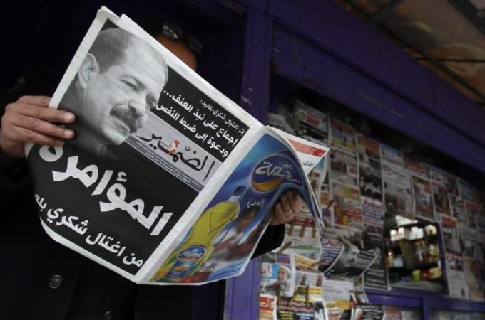 A man reads a local newspaper, displaying a picture of assassinated prominent Tunisian opposition politician Chokri Belaid, at a kiosk in Tunis