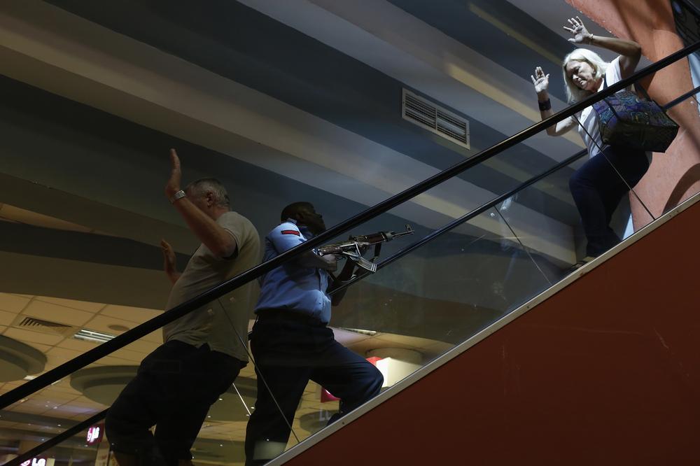 A police officer secures an area as civilians flee inside Westgate Shopping Centre in Nairobi