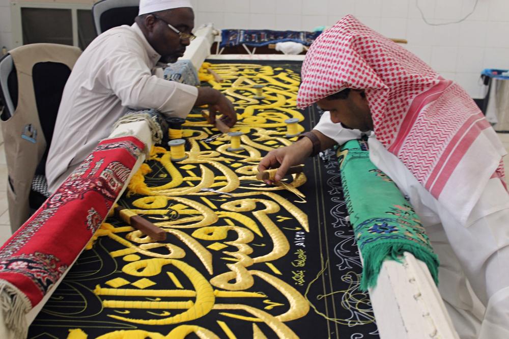 <p>Workers put the final touches on the Kiswa - the black cloth that covers the Kaaba. The Kiswa is adorned with embroidered calligraphers.</p>