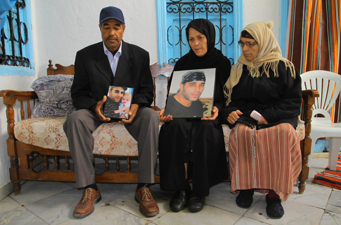 Family members hold pictures of Walid Denguir, 32, who died in police custody [Aymen Ben Mansour/Al Jazeera]