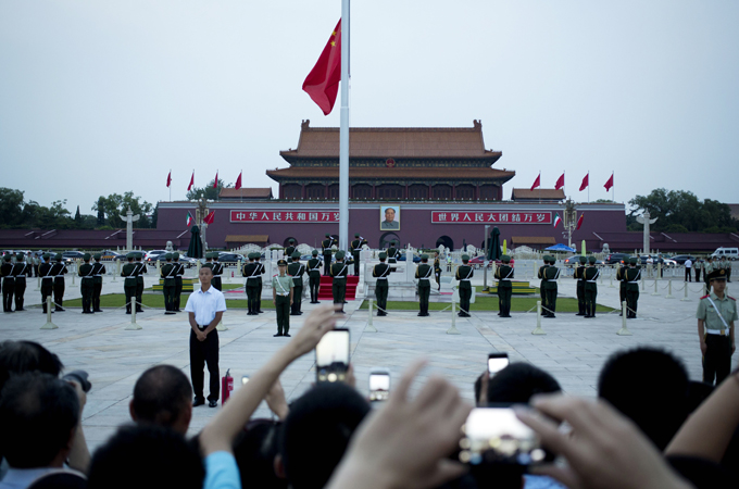 Chinese paramilitary policemen stand watch over visitors during the flag-lowering ceremony on the eve of the June 4 anniversary at Tiananmen Square in Beijing [AP]