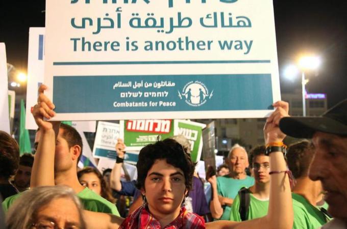 An Israeli holds a placard written in Arabic, Hebrew, and English during a peace protest in Rabin Square in Tel Aviv [EPA]