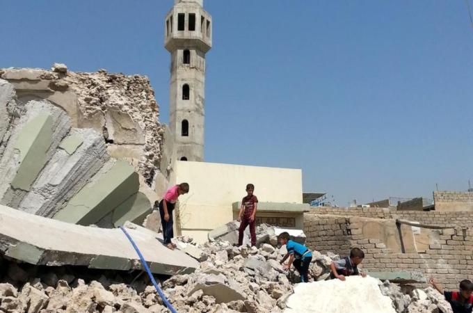 Iraqi boys stand over the rubble of the grave of a Sufi cleric in Mosul [EPA]