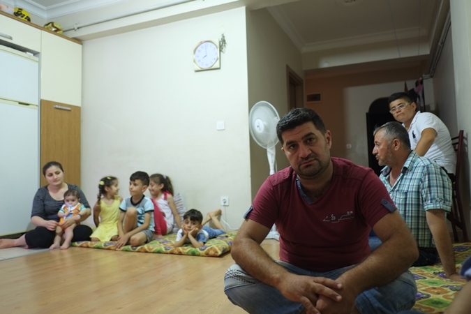 Gegeo spends his nights on the floor of an unfurnished apartment which he shares with his wife, three-year-old daughter and 22 extended family members [Noah Blaser/Al Jazeera]