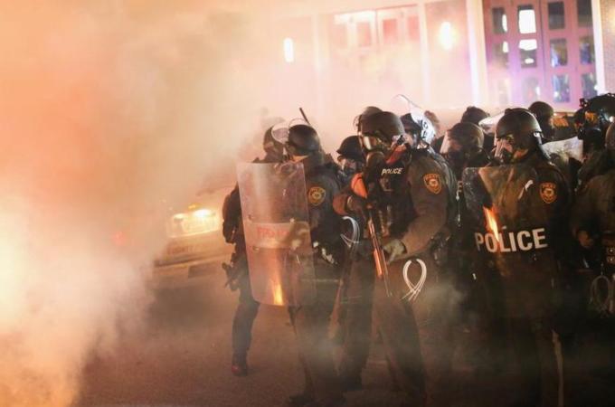 Police guard the Ferguson police department as rioting erupts [Getty Images]