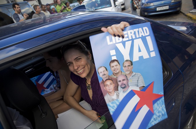 A woman with a poster of the Cuban Five, which reads in Spanish "Freedom Now," celebrates their release [AP]