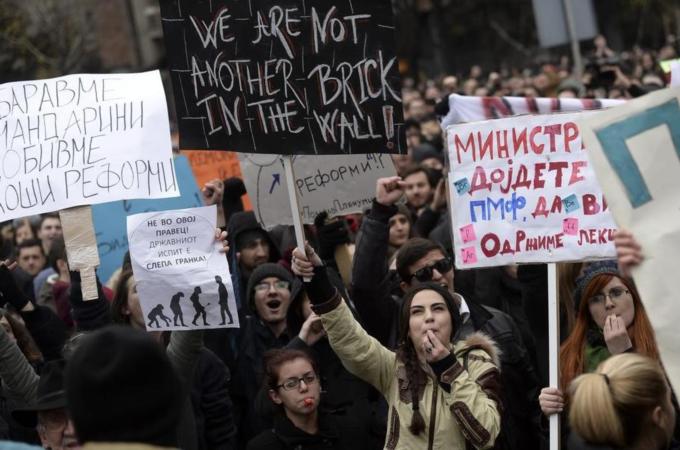 University students hold banners and shout slogans against government in protest against external state tests for university students in Skopje [EPA]