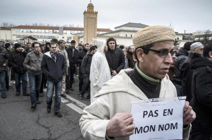A Muslim man holds a placard, reading 'Not in my name' in eastern France [AFP]