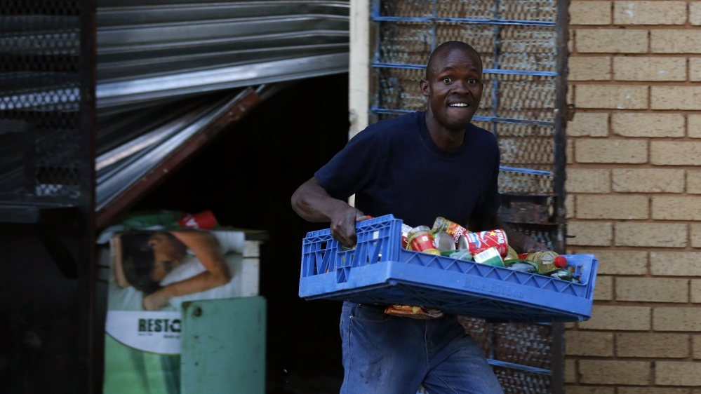 A man looks on as he runs with items from a shop believed to be owned by a foreigner, in Soweto