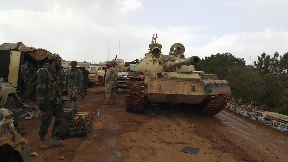 Members of Libyan pro-government forces, backed by locals, stand beside a tank at a rally point during nearby clashes with the Shura Council of Libyan Revolutionaries, in Benghazi