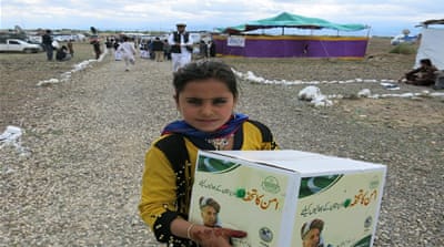 Fatima, 10, holds a box of clothes donated by the Punjab government to those returning home [Asad Hashim/Al Jazeera]
