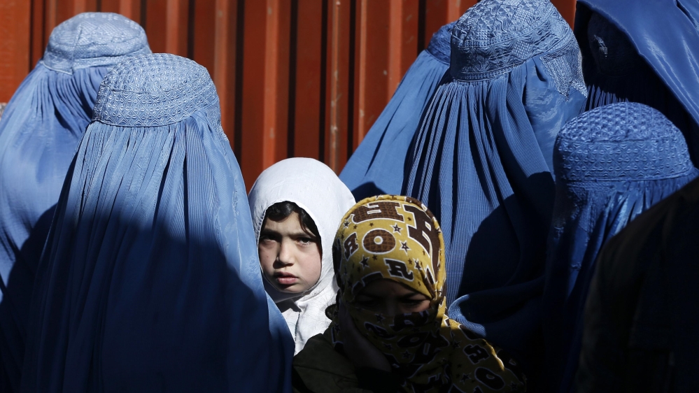 A girl looks on among Afghan women lining up to receive winter relief assistance donated by the United Nations High Commissioner for Refugees (UNHCR) in Kabul [Reuters]