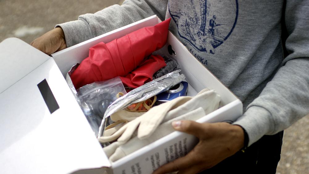 An open box of a Public Lab balloon mapping kit. The kit costs $80 and includes a 1.7 metre balloon and 305 metres of cable for collecting aerial images. The balloon is filled with helium and attached to the cable before being steadily floated skyward. A small camera holder with a tiny camera is affixed to the cable and then floated up high enough to gather aerial shots of a location before being brought back to ground.