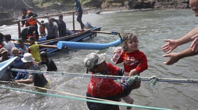 A rescuer carries a child after a boat carrying asylum seekers sank in Indonesian waters on the way to Australia [AP]