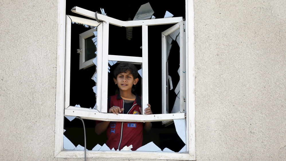 Boy looks through a window of his home damaged by an air strike near Sanaa Airport