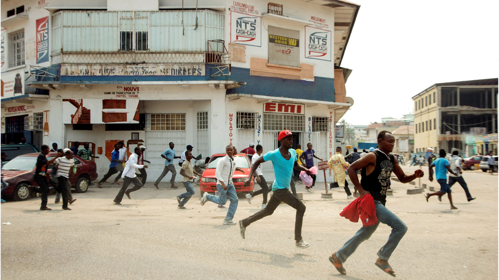 Protesters run in a street of Kinshasa