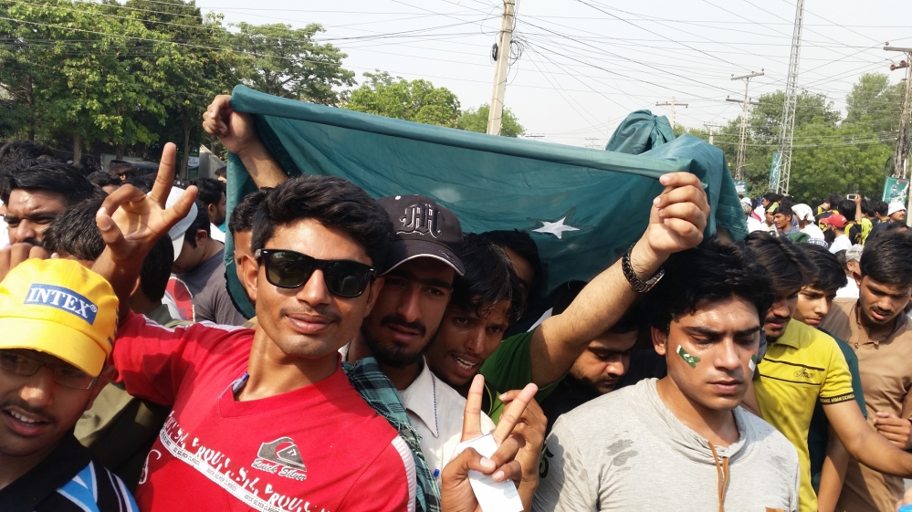Shahab Ahmed, far left, said that he had been waiting in 40+ degree heat for three hours to enter the stadium, but his spirit was undiminished [Asad Hashim/Al Jazeera]