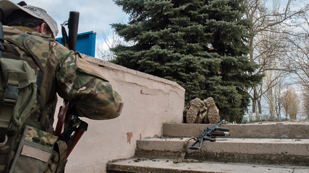 Two European ex-soldiers of the Azov Battalion move to avoid sniper fire on the front lines in Shyrokyne [Christopher Allen/Al Jazeera]