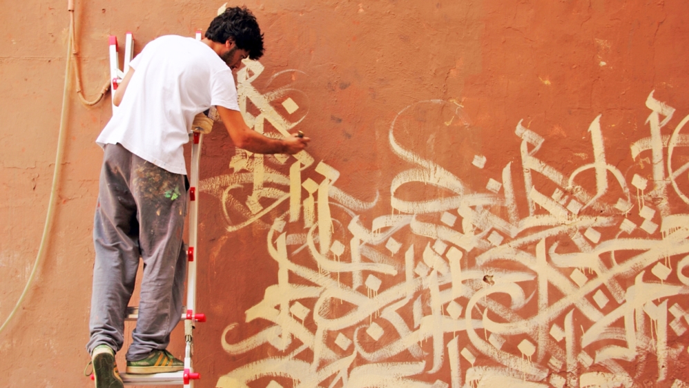 Halwani embellishing one of the walls of Beirut with Arabic calligraphy [Yazan Halwani/Al Jazeera]