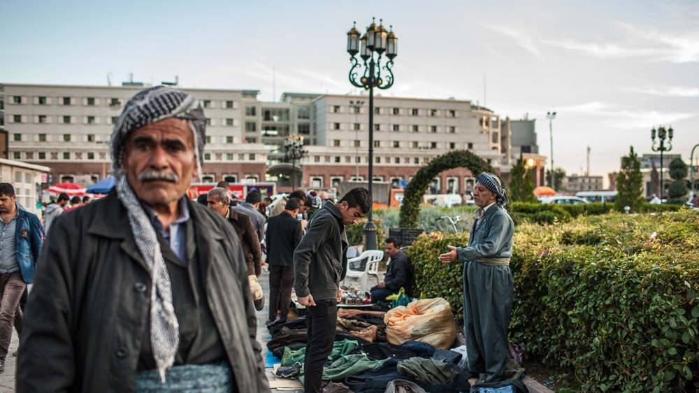 An elderly Kurdish man sells Western-style clothing to a young man in the centre of Erbil [Mackenzie Knowles-Coursin]