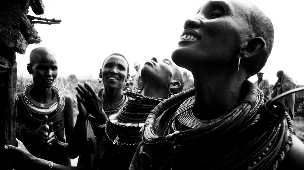 Following the excision, Juliana's mother, friends and relatives celebrate outside her hut as she is inside bleeding [Mariella Furrer]
