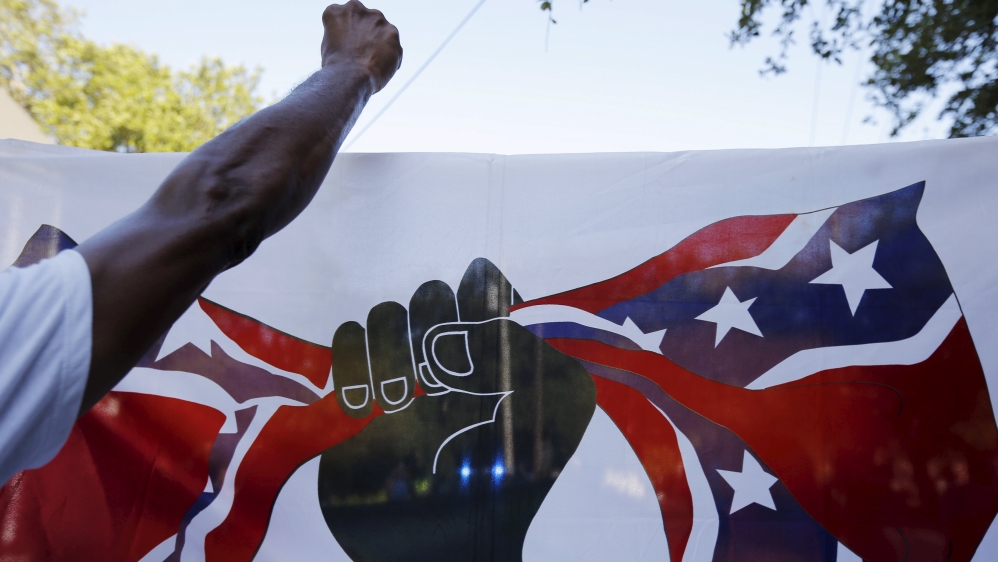 Demonstrators carry a flag showing a black fist closing around the confederate flag [REUTERS]