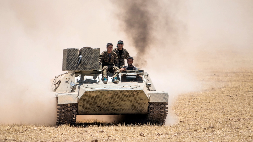 Kurdish People''s Protection Units (YPG) fighters drive a tank at the eastern entrances to the town of Tal Abyad in the northern countryside of Raqqa, Syria
