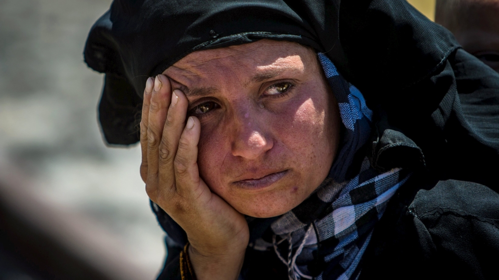 A woman rests after walking back to Tel Abyad town