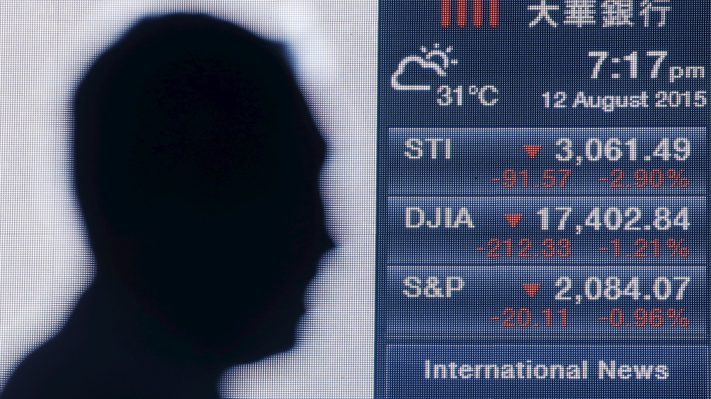 A man passes a board showing the Straits Times, Dow Jones and Standard and Poor indices at the central business district in Singapore
