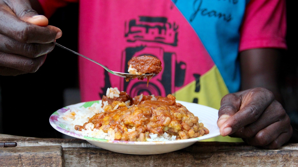Adamou eats rice and stewed beans for lunch. As money is tight, he buys lunch less regularly these days [Femke van Zeijl/Al Jazeera]