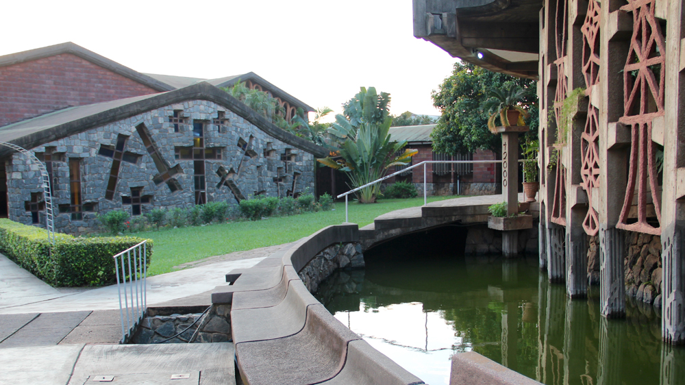 The pond encircling the back of the chapel, with a view of the lounge and the refectory behind the chapel [Femke van Zeijl/ Al Jazeera]