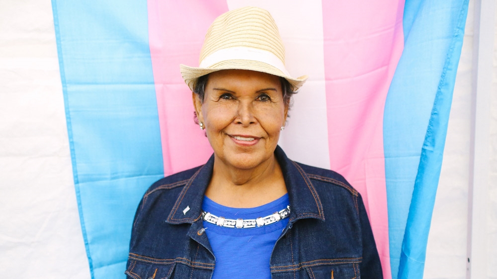 Felicia Flames stands in front of the trans* flag. Flames was an activist at the Compton Cafeteria Riot, the first documented instance of a trans riot in US history [Amanda Harris]