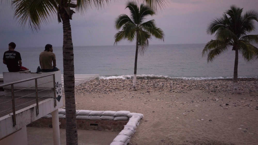 Two men sit out by the beach as hurricane Patricia