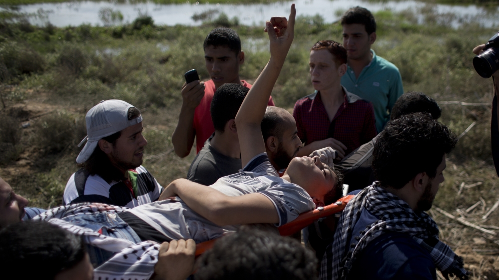 Palestinians carry a wounded man, during clashes with Israeli soldiers on the Israeli border Eastern Gaza City