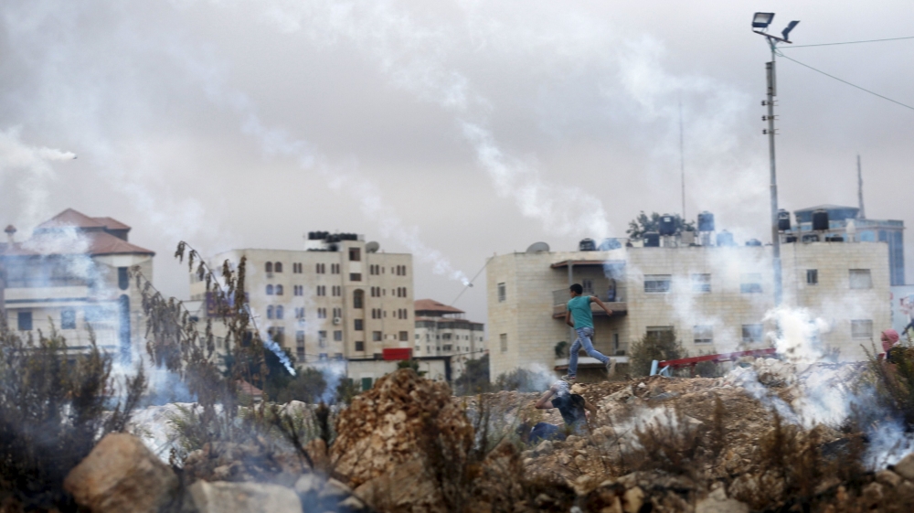 Palestinian boy runs away from tear gas fired Israeli troops during clashes near the Jewish settlement of Bet El, near the occupied West Bank city of Ramallah