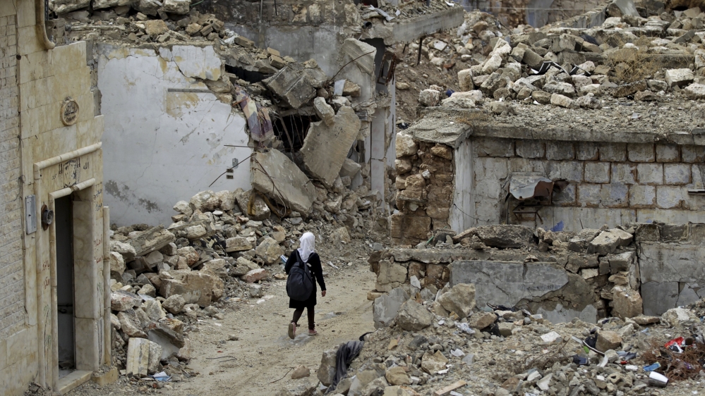 A school girl walks past damaged buildings in the rebel-controlled area of Maaret al-Numan town in Idlib province, Syria