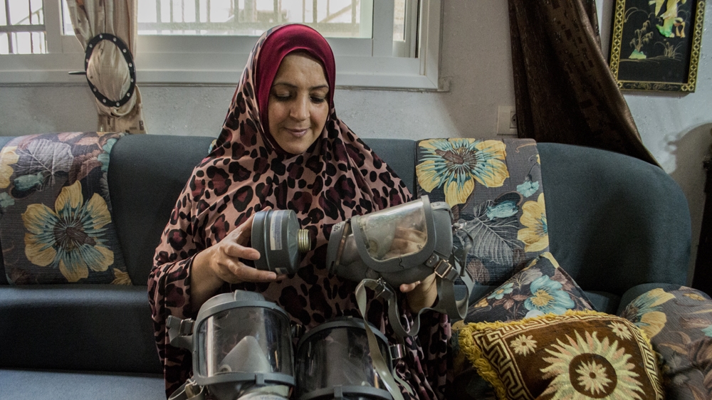 Raja Mustafa assembles the gas masks her teenage sons use during clashes [Abed al Qaisi/Al Jazeera] 