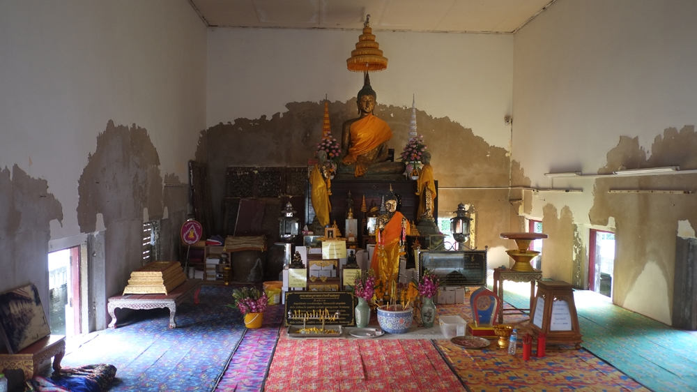 The interior of Wat Khun Samut Trawat with visible water damage. The temple was once the centre of village life, but now it stands alone [Jack Picone/Al Jazeera]