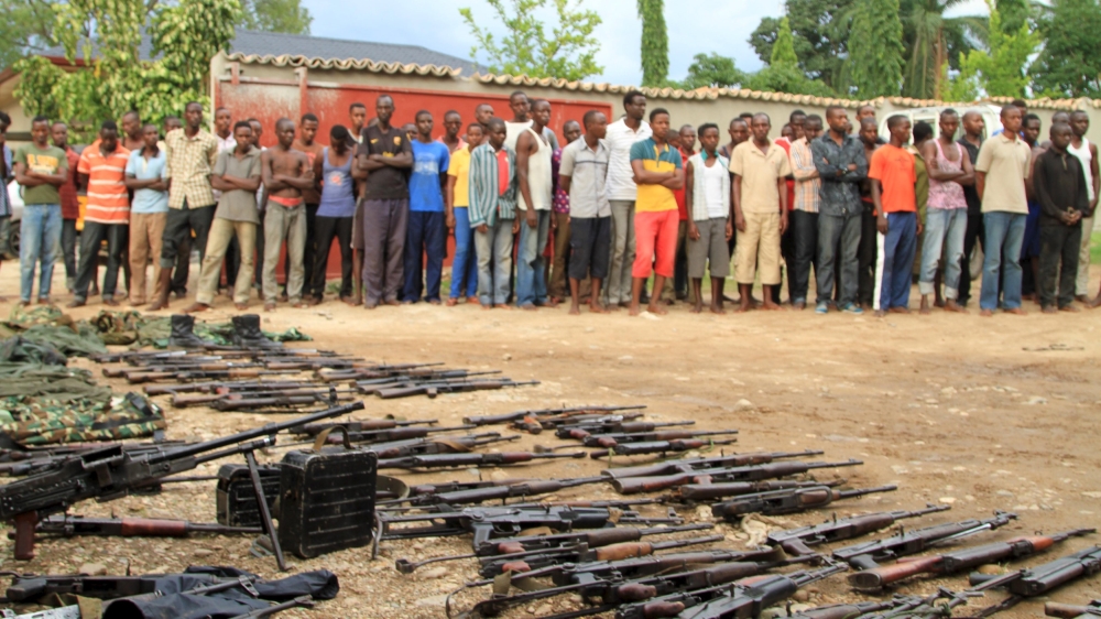 Suspected fighters are paraded before the media by Burundian police near a recovered cache of weapons [Reuters]