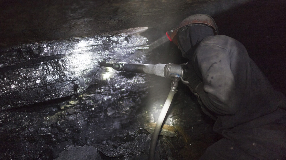 Twenty-three-year-old Tolek works several hundred metres below ground in an illegal mine in Davidovka. His job is to break the coal using a jackhammer, at the deep end of a dark tunnel, which is about half-a-metre in height. [Janos Chiala and Tali Mayer/Al Jazeera] 